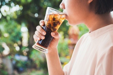 woman drinking a glass of cola with ice.