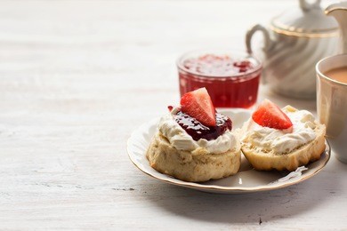 english tea with scones and clotted cream, jam, strawberries on the white table, copy space for text, selective focus