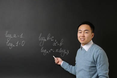 handsome asian teacher writing on blackboard