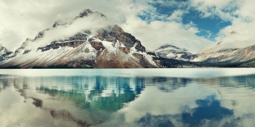 bow lake panorama reflection with snow capped mountain and forest in banff national park