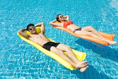 young couple relaxing on inflatable raft at swimming pool