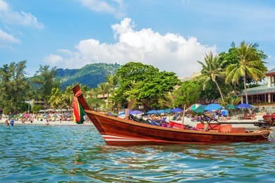 traditional thai long boat on kata beach - one of the best beaches in phuket, thailand 