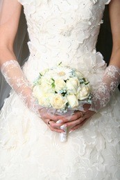 bride in a designer dress holding a rose bouquet.