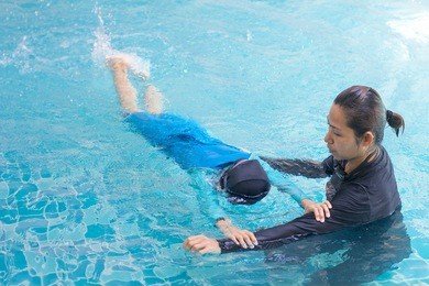 girl learning to swim with coach at the leisure center