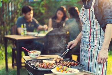 asian men are cooking for a group of friends to eat barbecue