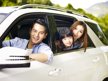 happy asian family traveling by car looking at camera smiling.