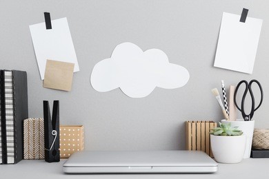 stylish workspace with laptop computer closed, office supplies, books, plant, at home or studio.