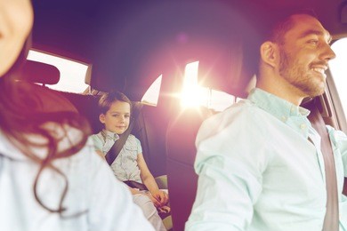 family, transport, safety, road trip and people concept - happy man and woman with little child driving in car