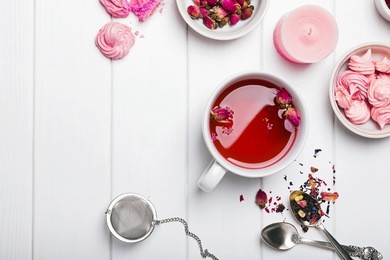 herbal tea with roses on white wooden table, top view