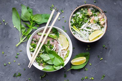 traditional vietnamese noodle soups pho in bowls, concrete background. vietnamese beef soup pho bo, chicken pho ga. close-up. asian/vietnamese food. vietnamese dinner. pho bo meal. top view. healthy
