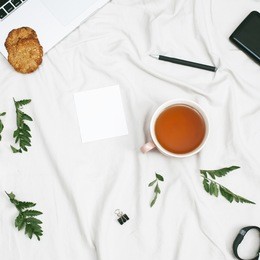 home office workspace frame with laptop, cup of tea, cookies, blanket and leaves. flat lay, top view. copy space. 