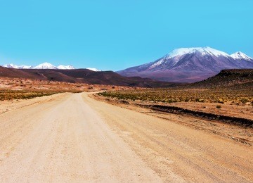 scenic landscape with road stretches into the distance on the background of snowy mountainson the bolivian altiplano
