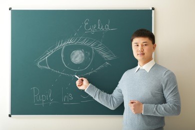 handsome young asian teacher on blackboard background
