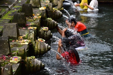 bali, indonesia - woman at the holy spring water is praying at pura tirta empul temple during a religious ceremony in tampa, bali, indonesia.