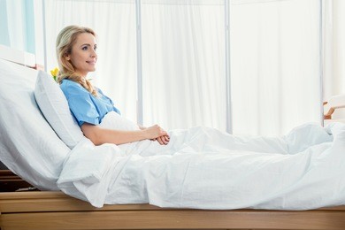 side view of smiling woman lying in hospital bed