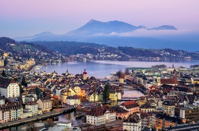 aerial view of the old town of lucerne, wooden chapel bridge, stone water tower, reuss river, rigi mountain and lake lucerne, switzerland, on sunset