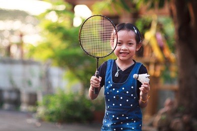smile little girl playing badminton at home.