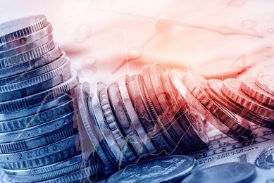 stack of coins on us dollar notes with analog clock hands and a technical chart of financial instruments. concept of time value of money, any amount of money is worth more the sooner it is received. 
