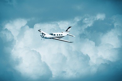 single piston aircraft. single-propeller aircraft flying over the blue sky. single turboprop aircraft.. small private plane flying in blue clouds.