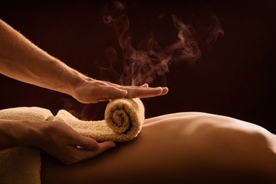 a professional therapist applies a hot towel on the back of a man. hot towel compress. spa treatment
