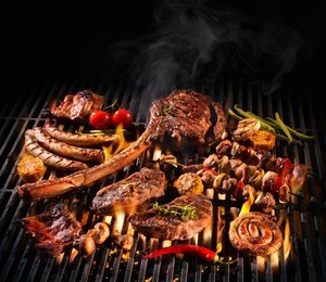 assorted delicious grilled meat with vegetables over the coals on a barbecue