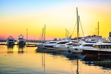 luxury yachts docked in sea port at colorful sunset. marine parking of modern motor boats.