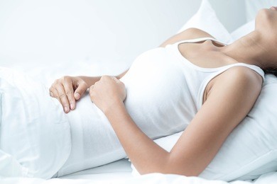 woman lying on the bad having stomach ache