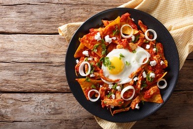 mexican nachos with tomato salsa, chicken and egg close-up on a plate. horizontal view from above
