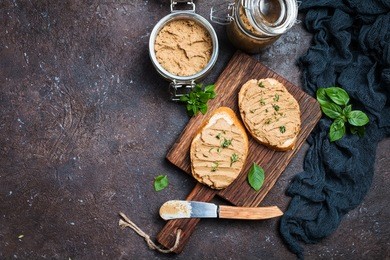fresh homemade chicken liver pate on bread over rustic background, top view