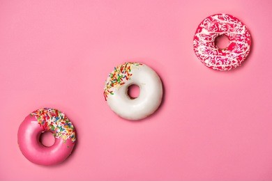 donuts with icing on pastel pink background. sweet donuts.
