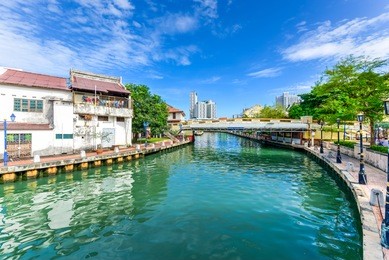 empty river with small pedestrian bridge during a sunny cloud blue sky in melaka, a unesco world heritage site since 7 july 2008. rustic walkway along the historical river town of malacca, malaysia.