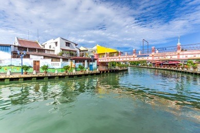 empty river with small pedestrian bridge during a sunny cloud blue sky in melaka, a unesco world heritage site since 7 july 2008. rustic walkway along the historical river town of malacca, malaysia.