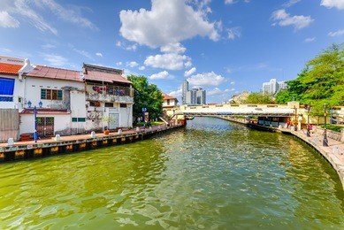 empty river with small pedestrian bridge during a sunny cloud blue sky in melaka, a unesco world heritage site since 7 july 2008. rustic walkway along the historical river town of malacca, malaysia.
