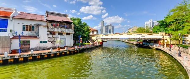 empty river with small pedestrian bridge during a sunny cloud blue sky in melaka, a unesco world heritage site since 7 july 2008. rustic walkway along the historical river town of malacca, malaysia.