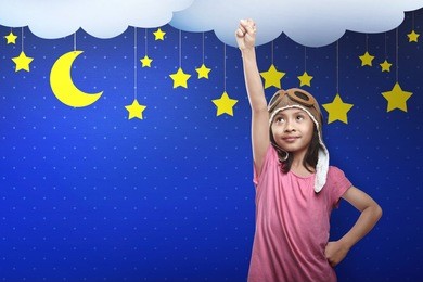 asian child in astronaut costume dreaming of becoming a spaceman with yellow stars on blue wall background