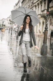 portrait of beautiful woman dancing in the rain with umbrella, splash in puddle