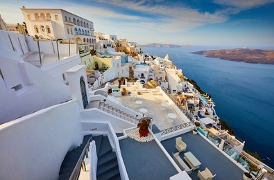 fira town on santorini island, greece. traditional and famous houses and churches with blue domes over the caldera, aegean sea. terraces of santorini hotels in the morning light.