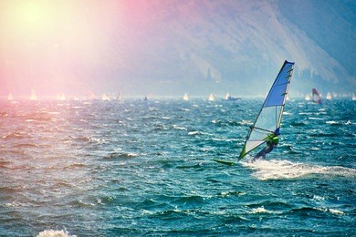 windsurfer surfing the wind on waves in garda lake, recreational water sports, extreme sport action. recreational sporting activity. healthy active lifestyle. summer fun adventure. hobby