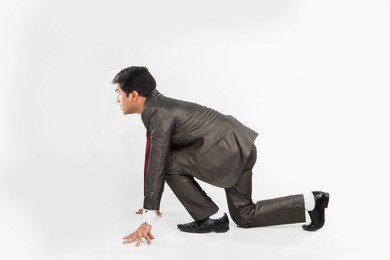 young indian/asian smart and determined businessman running or standing in start position, isolated over white