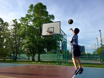 boy playing basketball at the park in the morning.