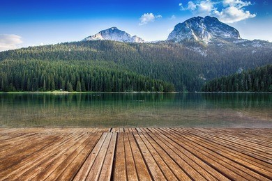 old wooden pier with crystal clear lake. montenegro, national park durmitor, mountains and clouds. nature travel background