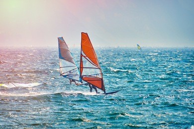 windsurfer surfing the wind on waves in garda lake, recreational water sports, extreme sport action. recreational sporting activity. healthy active lifestyle. summer fun adventure. hobby