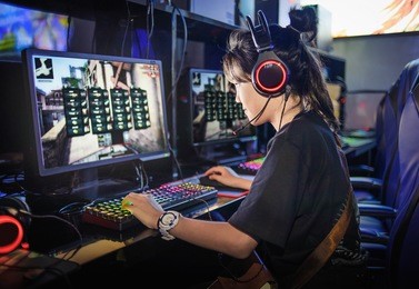 young girl playing computer games in internet cafe