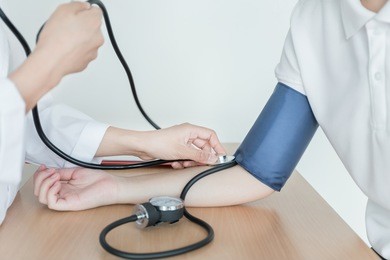doctor using sphygmomanometer with stethoscope checking blood pressure  to a patient in the hospital.