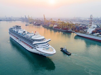 cruise passenger ship in time of departure to the sea from main entrance channel due of the port, in the morning sunrise in aerial view