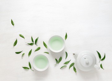 tea freshly brewed in a teapot and two cups, surrounded with fresh tea leaves, top view composition, space for a text