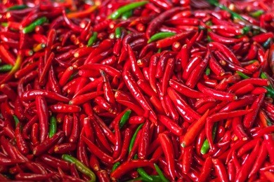 pile of fresh red chilli peppers texture. raw food background. close up. traditional vegetable market in bangkok, thailand.