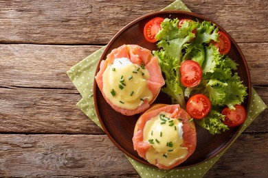 hearty breakfast: poached eggs with salmon and hollandaise sauce on a plate close-up. horizontal view from above
