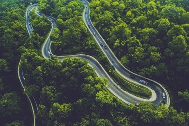 a winding road between tropical forests is visible from the air in north sumatra, indonesia.