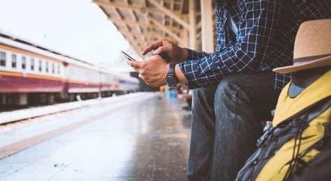 young traveler man using a smartphone for planning the trip in bangkok train station